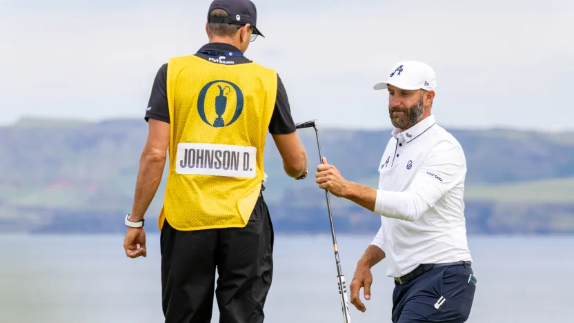 Captain Dustin Johnson of 4Aces GC gives his putter to caddie, Austin Johnson, on the fifth green during the second round of The Open Championship at Royal Portrush Golf Club on Friday, July 18, 2025 in Portrush, Northern Ireland. (Photo by LIV Golf)