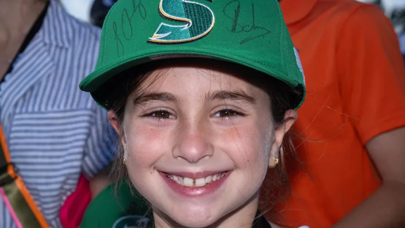A young fan poses for a photo with a Stingers GC autographed hat during the LIV to Learn activation during the practice round before the start of LIV Golf Miami at the Trump National Doral on Wednesday, April 03, 2024 in Miami, Florida. (Photo by Charles Laberge/LIV Golf)